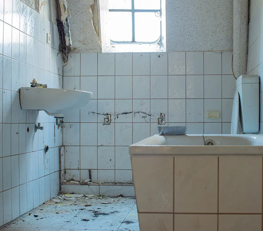 Abrissreifes altes Badezimmer mit weißen Fliesen