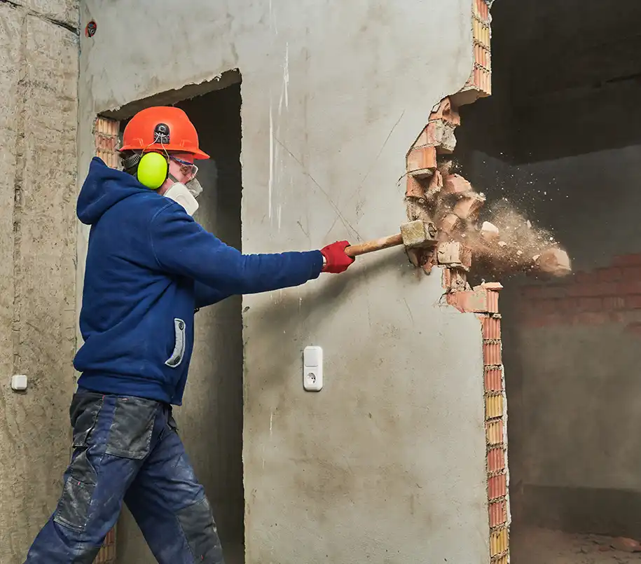 Arbeiter mit Vorschlaghammer beim Abriss einer Innenwand