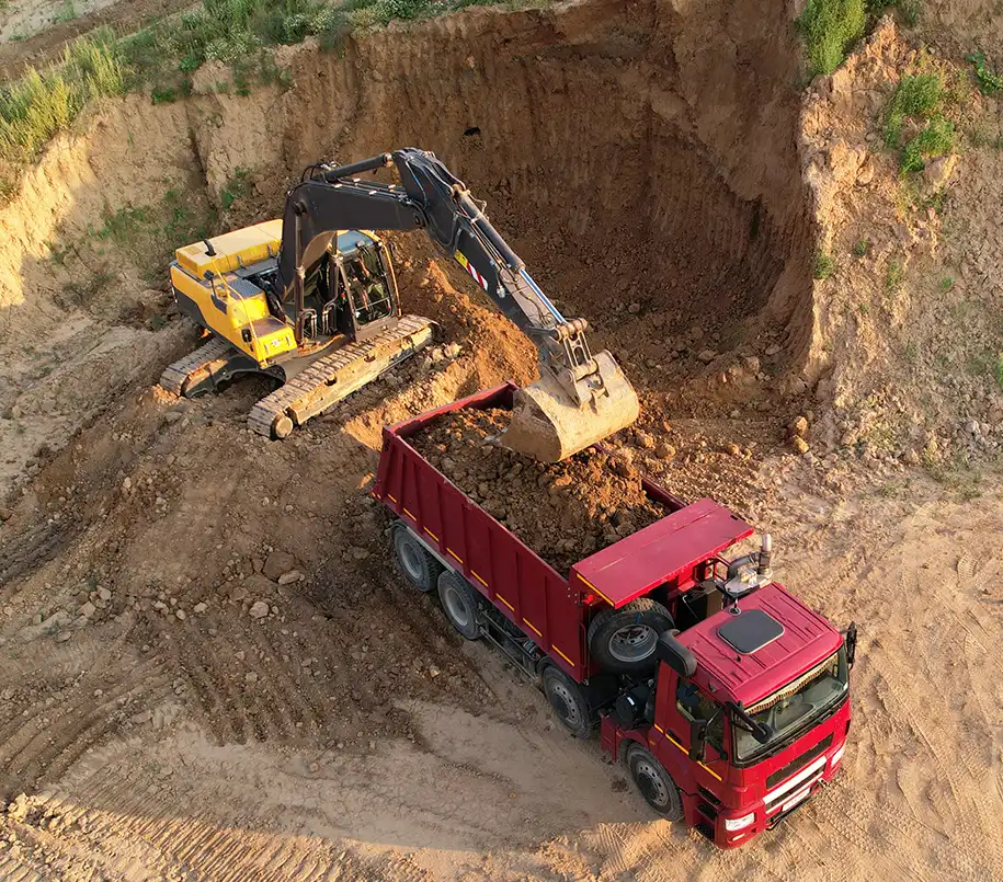 Bagger verfüllt Erdreich in einen Lastwagen