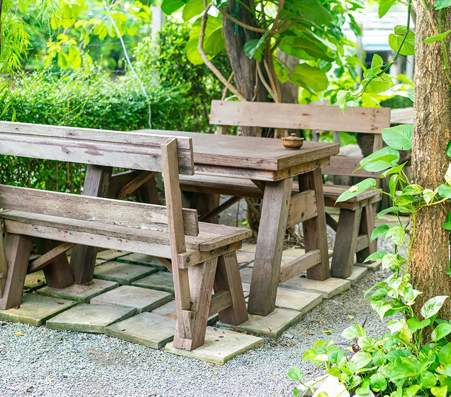 Alte Gartenmöbel aus Holz stehen auf verfallener Gartenterrasse